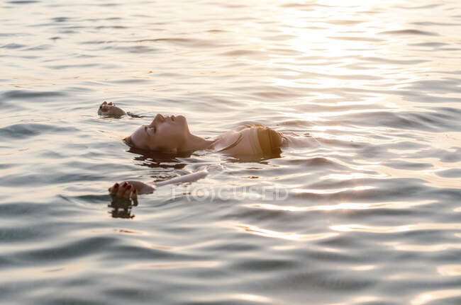 Jovem mulher flutuando de volta no mar — Fotografia de Stock