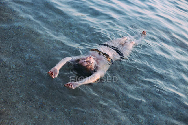 Jovem mulher flutuando de volta no mar — Fotografia de Stock