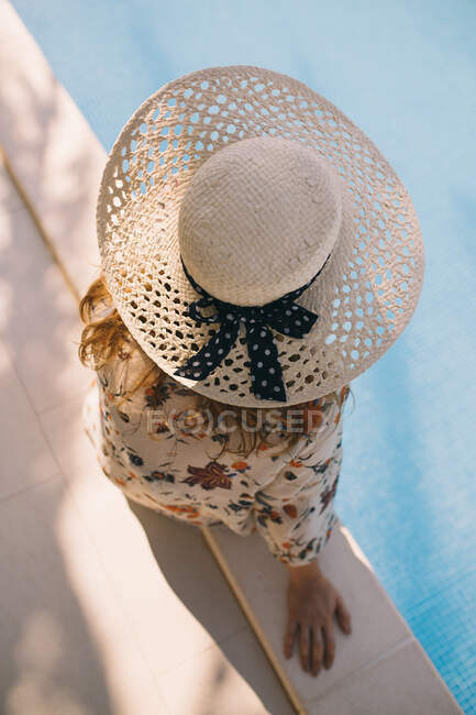 Close up vista superior da mulher com chapéu sentado à beira da piscina — Fotografia de Stock