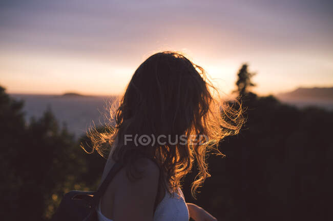 Молода жінка з хвилястим волоссям на заході сонця — стокове фото