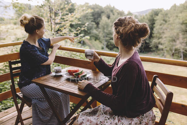 Две женщины сидят на балконе и пьют кофе — стоковое фото
