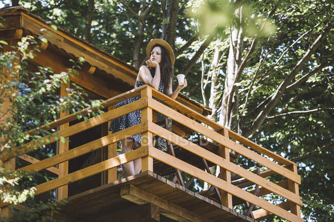 Молода жінка стоїть на балконі дерев'яного будинку — стокове фото