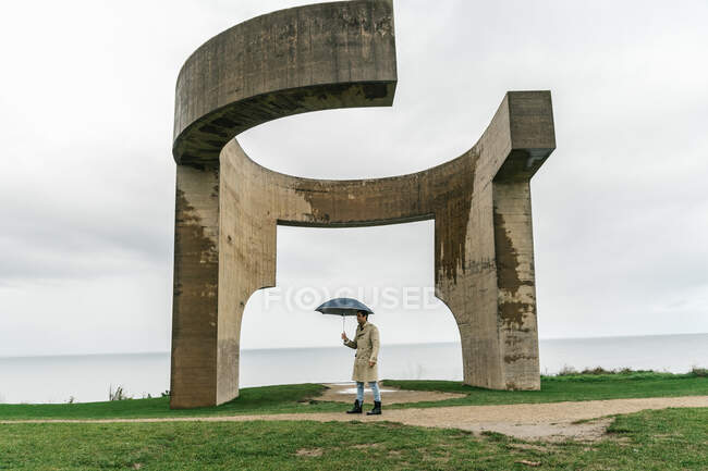 Силуэт человека с зонтиком у памятника 
