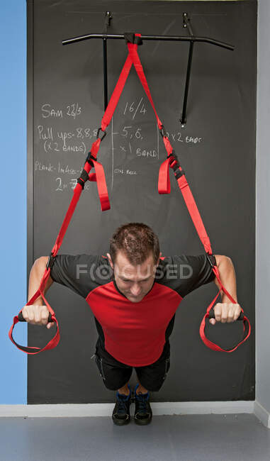 Fit man performing suspension training in gym in the UK — Stock Photo