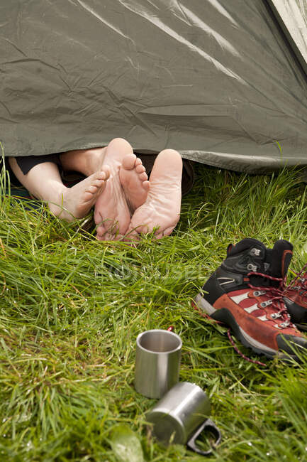 Feet of couple cuddling in tent in England — Stock Photo