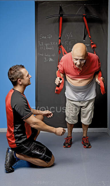 Personal trainer aiutare il cliente con l'allenamento di sospensione in palestra — Foto stock