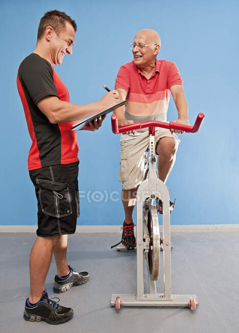 Personal trainer with senior client at gym in the UK — Stock Photo