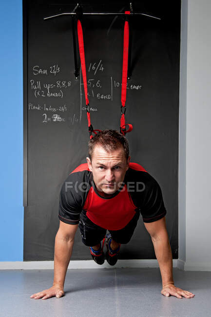 Entrenador personal mostrando entrenamiento de suspensión en el gimnasio - foto de stock