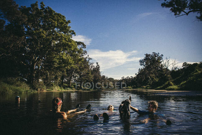 Eine Familie kühlt sich in einem Fluss während einer Hitzewelle mit einem Windhund ab — Stockfoto