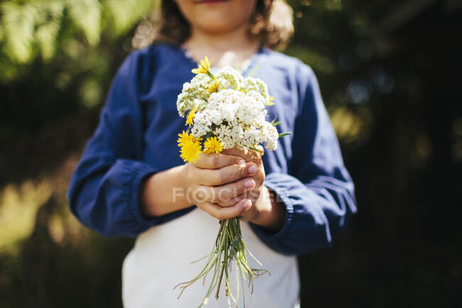 Ein junges Mädchen hält einen Strauß Wildblumen auf einer Koppel — Stockfoto