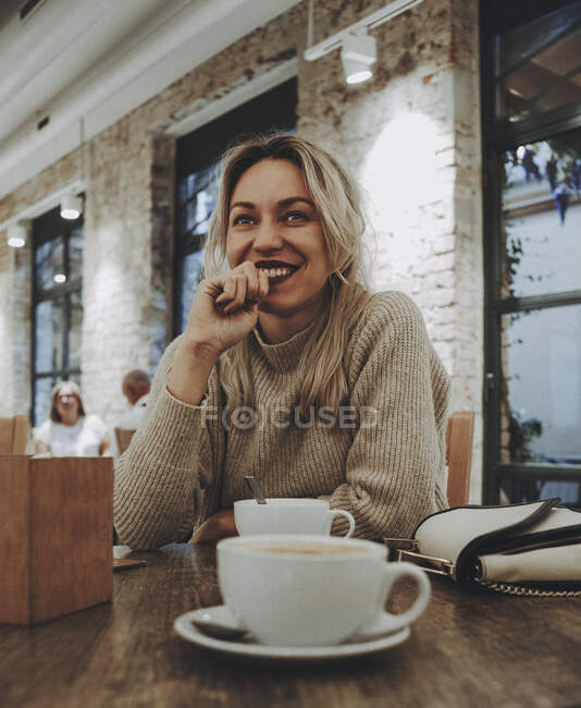 Retrato de una mujer rubia sonriendo a un café. - foto de stock