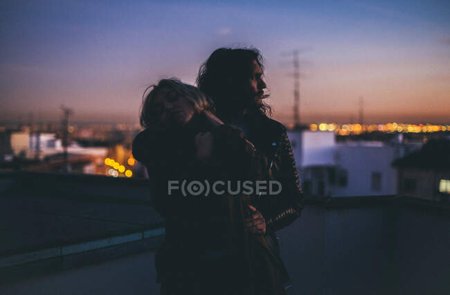 Elegante pareja abrazándose a la luz azul. - foto de stock