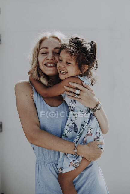 Mamá e hija cariñosamente abrazadas, riendo. - foto de stock