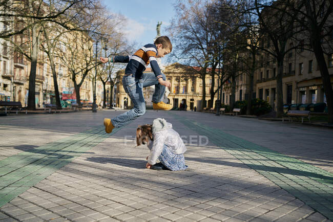 Emocionado chica y chico jugando en la calle - foto de stock