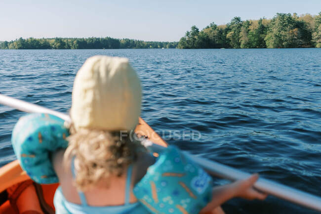 Little girl trying to paddle in a kayak. — Stock Photo