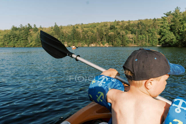 Маленький хлопчик намагається використати весло каяка . — стокове фото