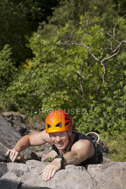 Man climbing up steep rock face in south Wales — Stock Photo