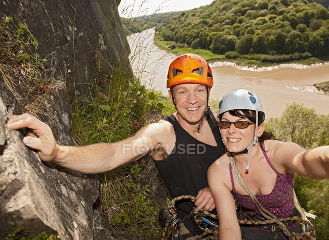 Pareja escalando empinada cara de roca en el sur de Gales - foto de stock