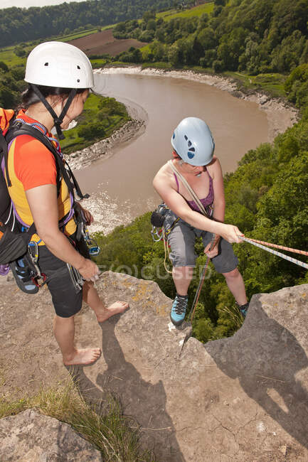 Amiga supervisando a su amiga mientras desciende escarpado acantilado en Gales - foto de stock