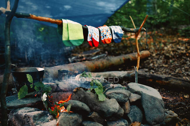 Drying wet socks on the bonfire during camping. Socks drying on fire. Active rest in forest. Adventure — Stock Photo