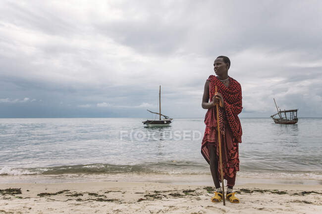 Man in traditional clothes with a sword on the beach — Stock Photo