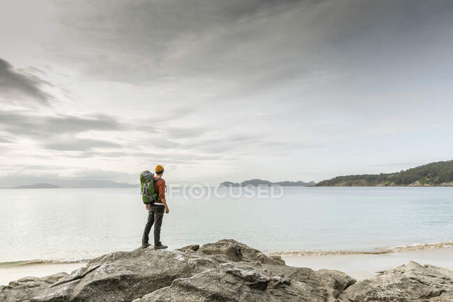 Homem com mochila desfrutando da vista da manhã da costa — Fotografia de Stock
