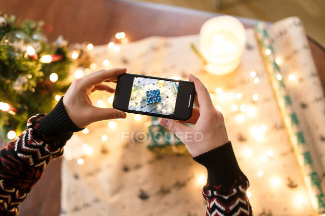 Hombre tomando fotos en el teléfono inteligente cuidadosamente envuelto regalo de Navidad - foto de stock