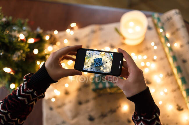Man taking pictures on smartphone carefully wrapped Christmas present — Stock Photo