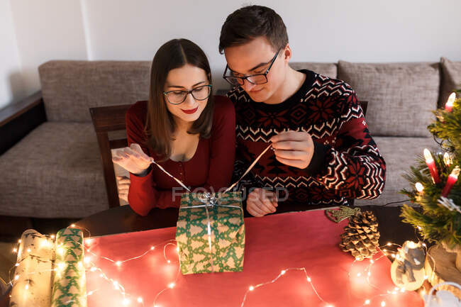 Pareja joven enamorada de los regalos de Navidad en un ambiente festivo - foto de stock