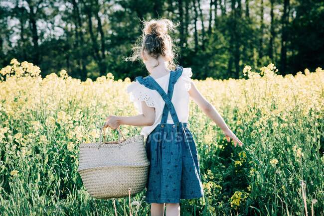 Jeune fille collecte des fleurs dans un panier dans un champ de fleurs en Suède — Photo de stock
