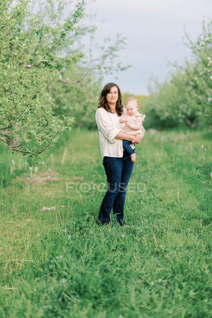 Una madre sosteniendo orgullosamente a su hija en sus brazos - foto de stock