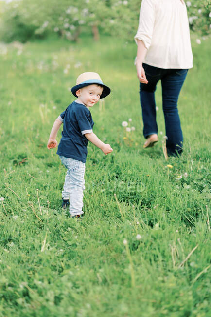 Милий хлопчик-малюк дивиться в камеру під час прогулянки зі своєю мамою — стокове фото