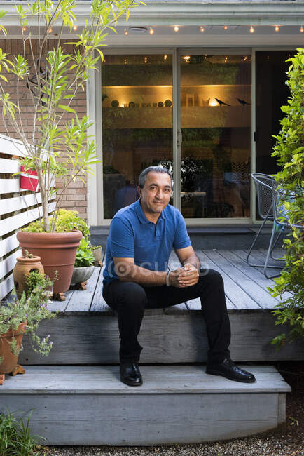 Sorrindo Homem hispânico sentar-se no convés em frente a sua casa — Fotografia de Stock