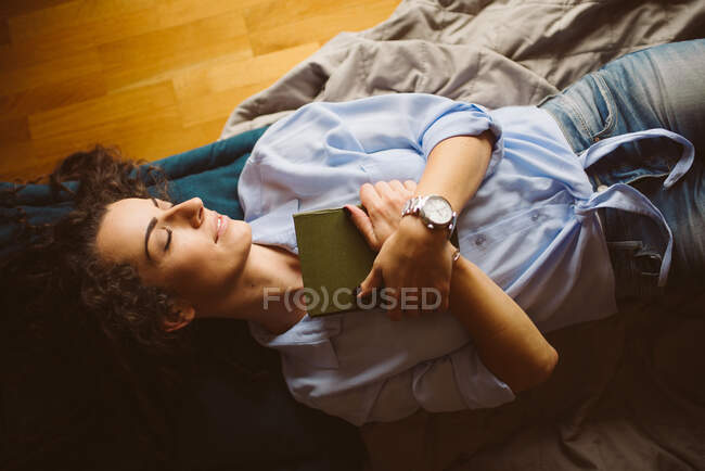 Jeune femme avec livre couché dans la salle de lumière — Photo de stock