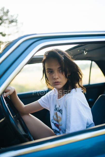 Молодая женщина сидит в припаркованной винтажной машине. — стоковое фото