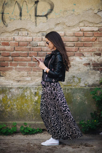 Привлекательная женщина в платье смотрит на смартфон снаружи — стоковое фото