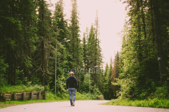 Il concetto di camminare da soli. Giovane uomo biondo caucasico in jeans passeggiate — Foto stock