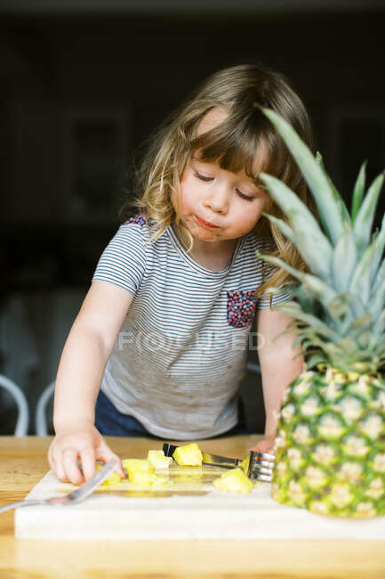 Une petite fille tout-petit ayant une collation d'ananas saine — Photo de stock
