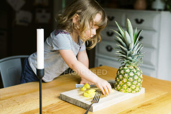 Una niña pequeña comiendo un bocadillo de piña saludable - foto de stock
