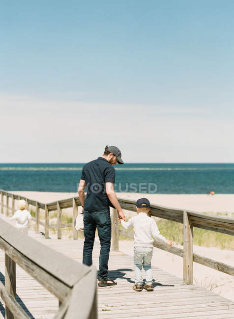 Батько тримає сина за руку на пляжі — стокове фото
