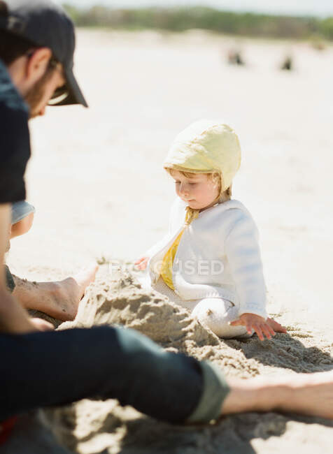 Un padre y su hija construyendo un castillo de arena - foto de stock