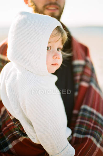 A little toddler girl in the arms of her father at the beach — Stock Photo