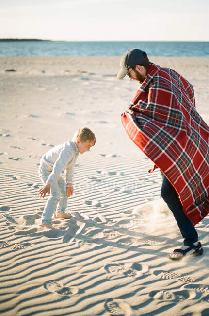 Ein kleiner Junge und sein Vater spielen mit Sand am Strand — Stockfoto
