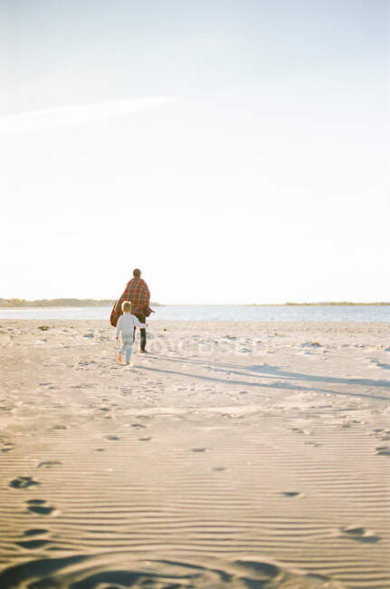 Маленький хлопчик і його батько грають мітку на пляжі — стокове фото