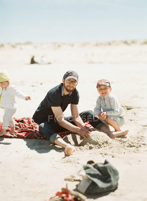 A happy family building sand castles at the beach — Stock Photo