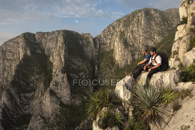 Dos amigos sentados en una roca en un punto alto en La Huasteca - foto de stock