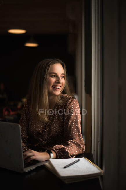 Giovane blogger influencer che lavora in una caffetteria vicino ad una finestra — Foto stock