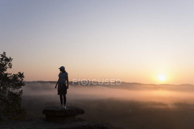 Silhouette eines Mädchens, das bei Sonnenaufgang auf einem Berggipfel wandert — Stockfoto