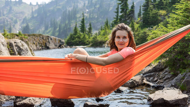 Femme se relaxe dans un hamac au bord du lac alpin en vacances locales — Photo de stock