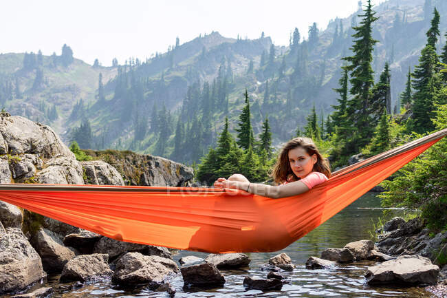Frau guckt im Urlaub aus Hängematte am Bergsee — Stockfoto